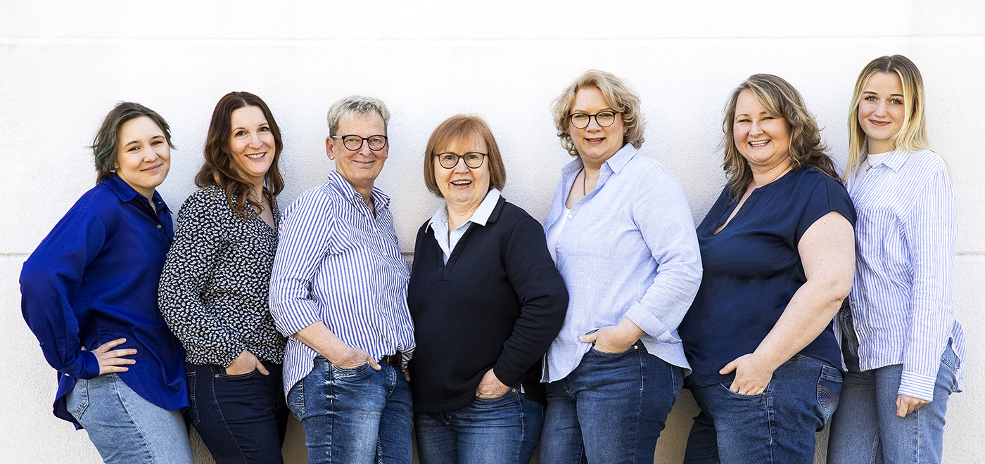 das ganze Team, 7 weibliche Personen stehen zusammen vor einer weißen Wand